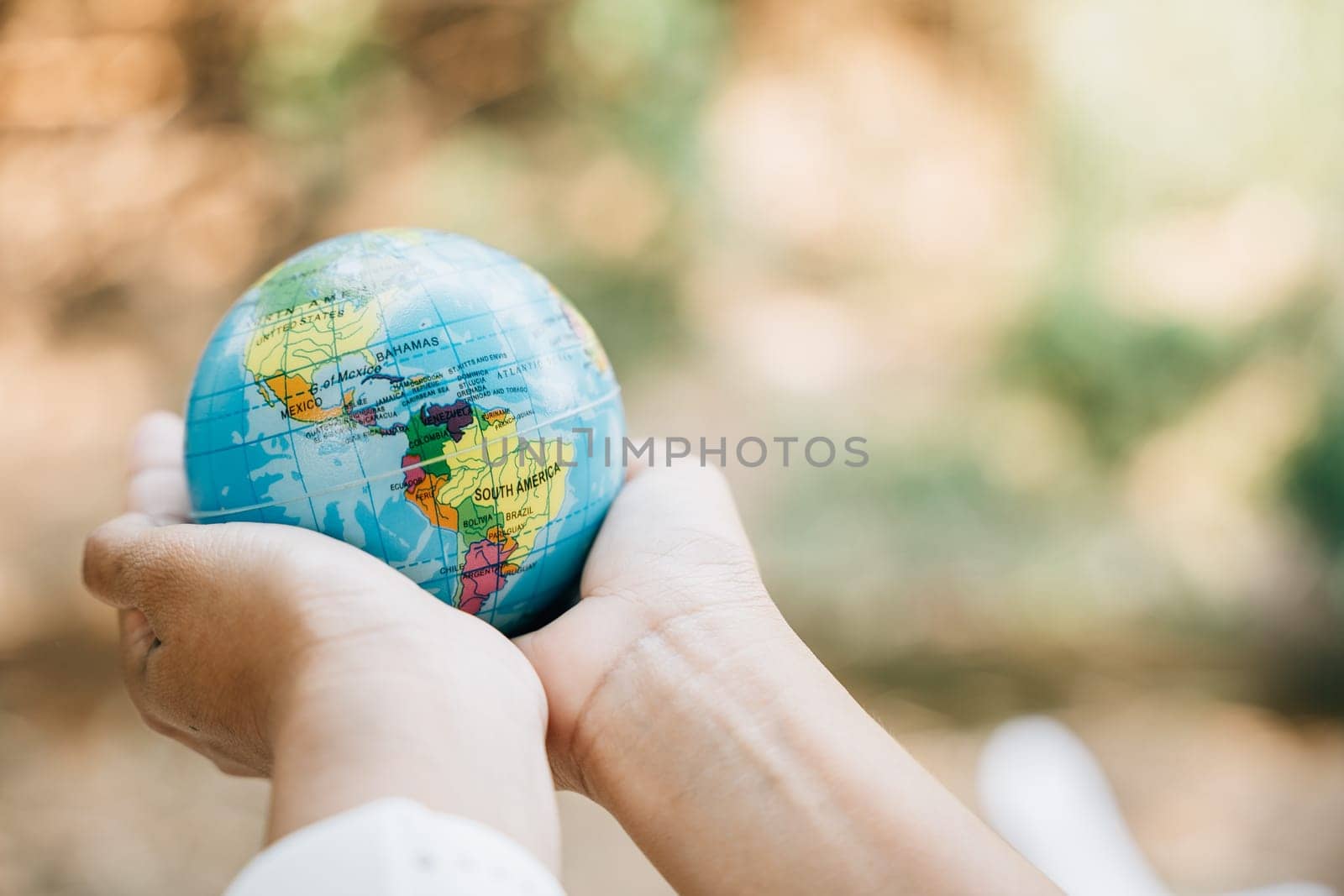 Celebrate World Earth Day with the concept of Green Energy, ESG, and Sustainable Resources. Hold a green leaf and the globe in your hand to signify responsibility and environmental care. by Sorapop