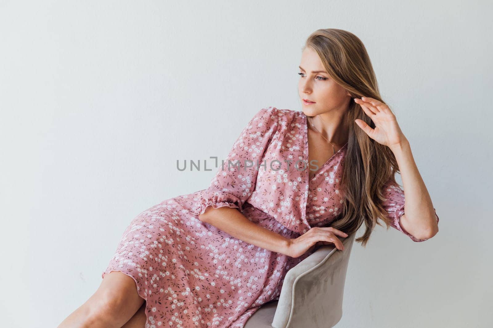 woman in a dress sits in a chair on a white background