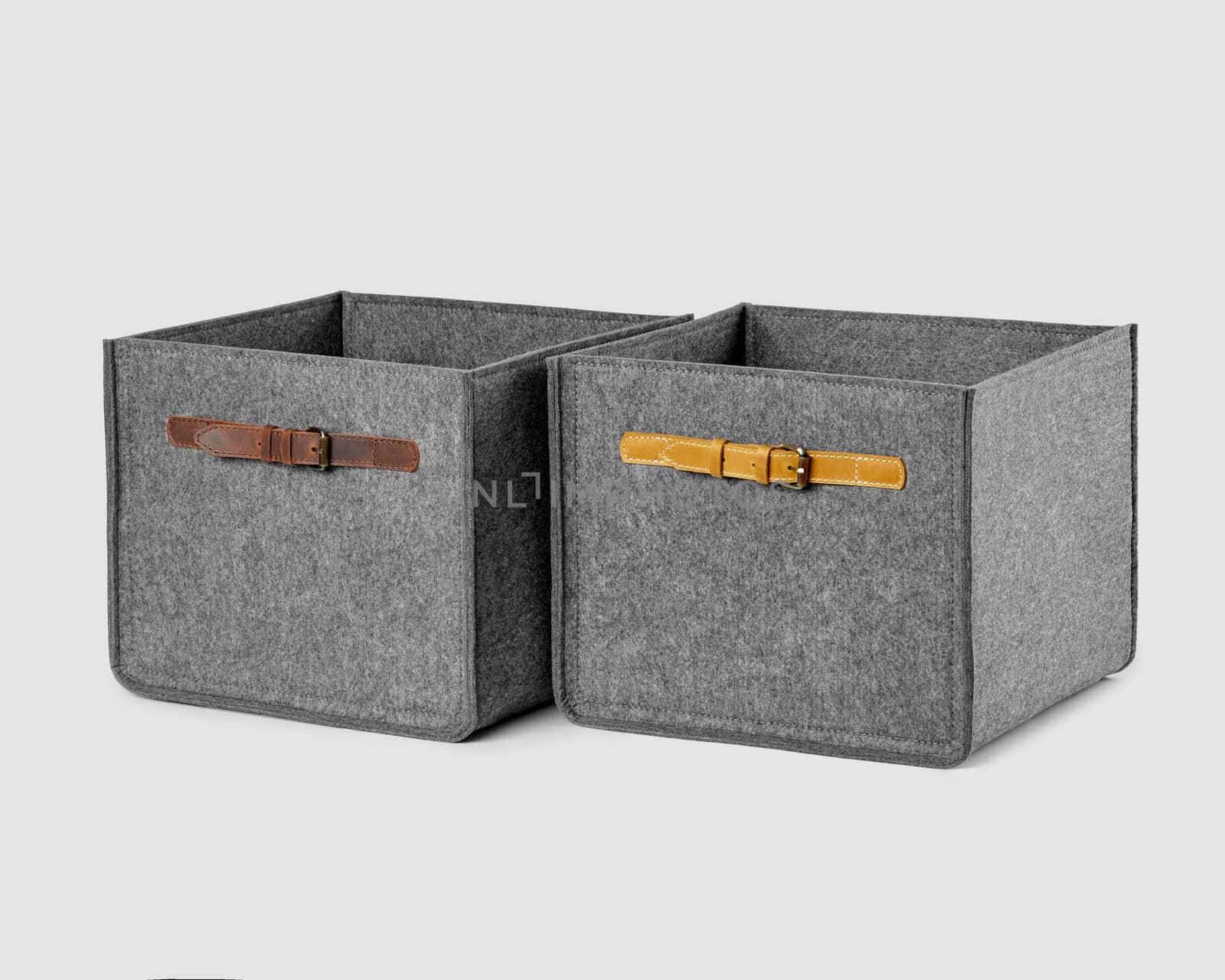 Functional baskets made of gray felt with sewn-on leather handles on sides for organizing home space and storing things. Stylish artisanal interior accessories