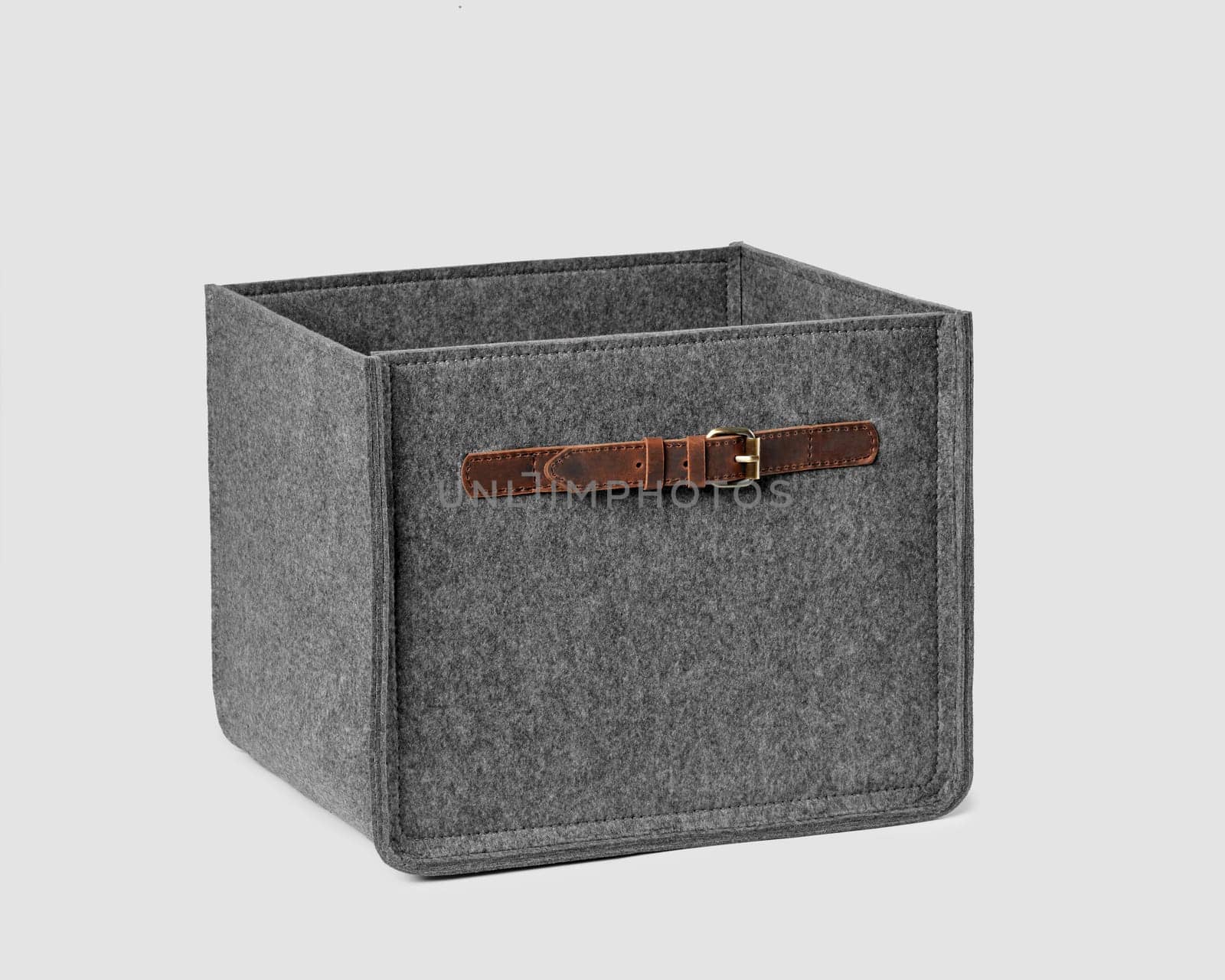 Functional storage box of natural gray felt with leather handles for carrying and storing things in modern home space. Artisanal accessories for interior design