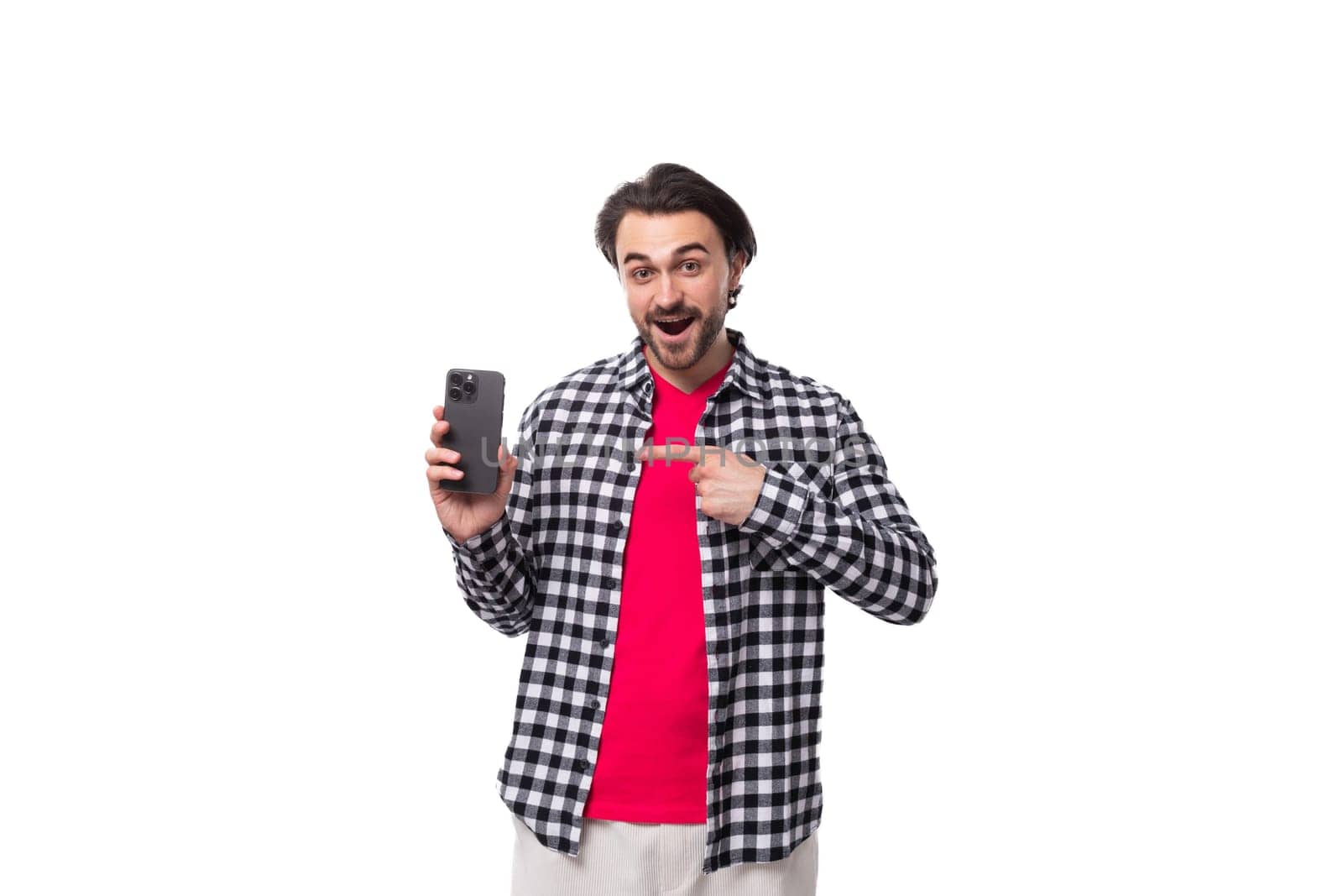 young european man with black hair and beard holding smartphone with screen mockup isolated on white background with copy space.