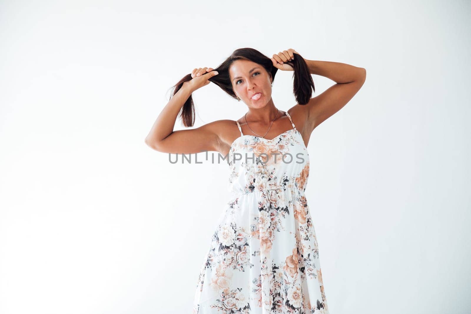 woman in a floral dress holds her hair with her hands