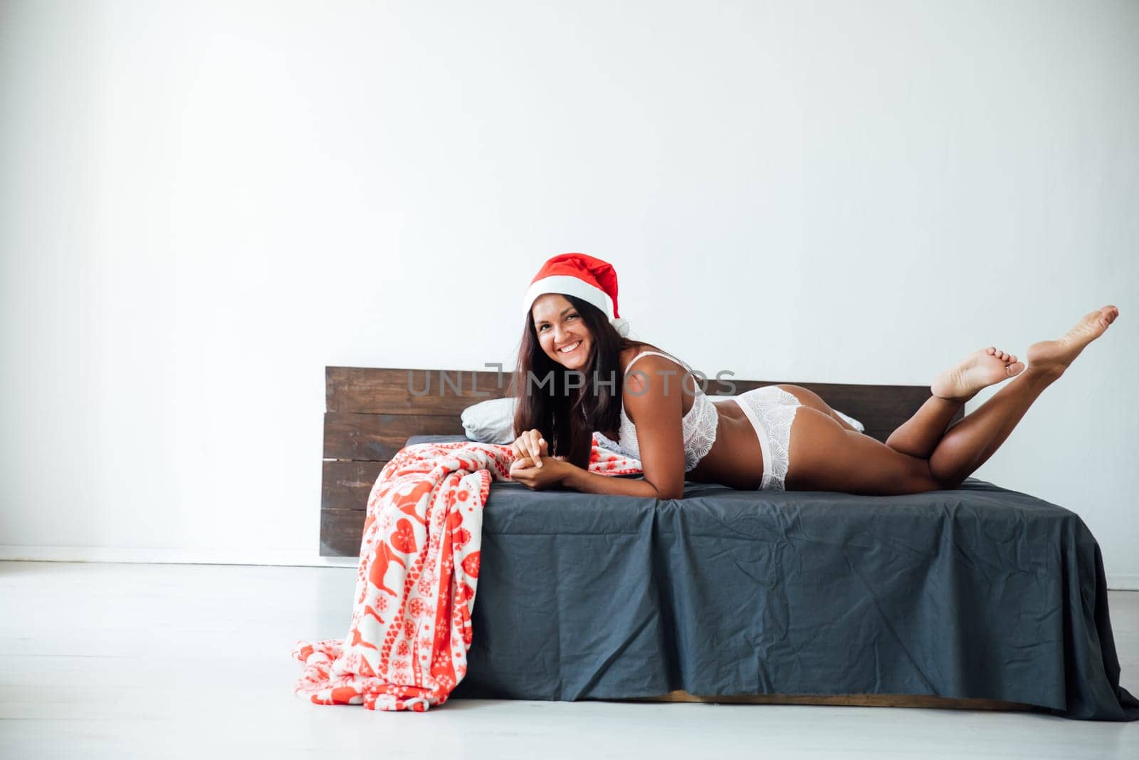 woman in underwear in a Christmas cap lies on the bed in the bedroom