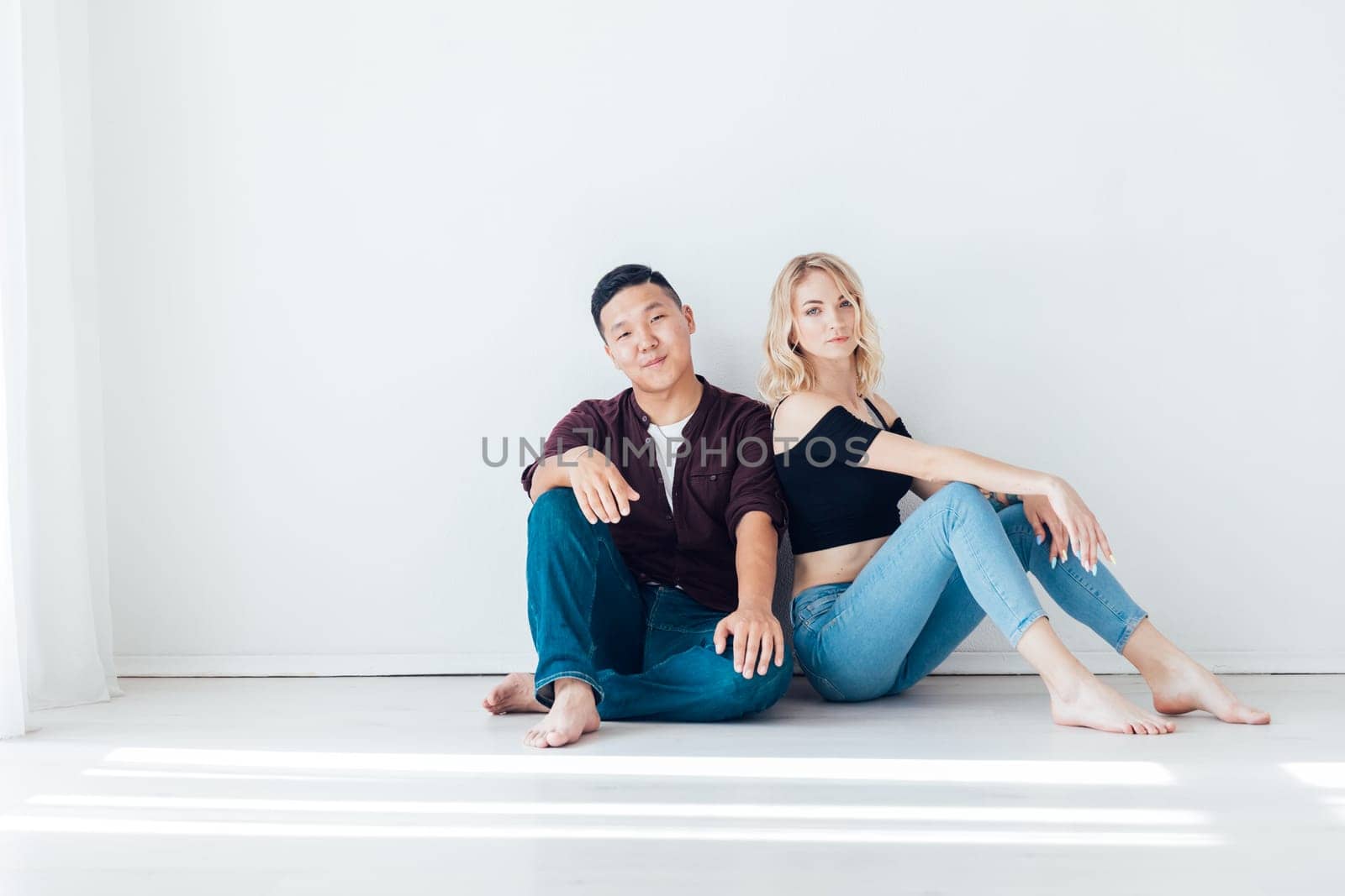 man and a woman couple sit against a light wall