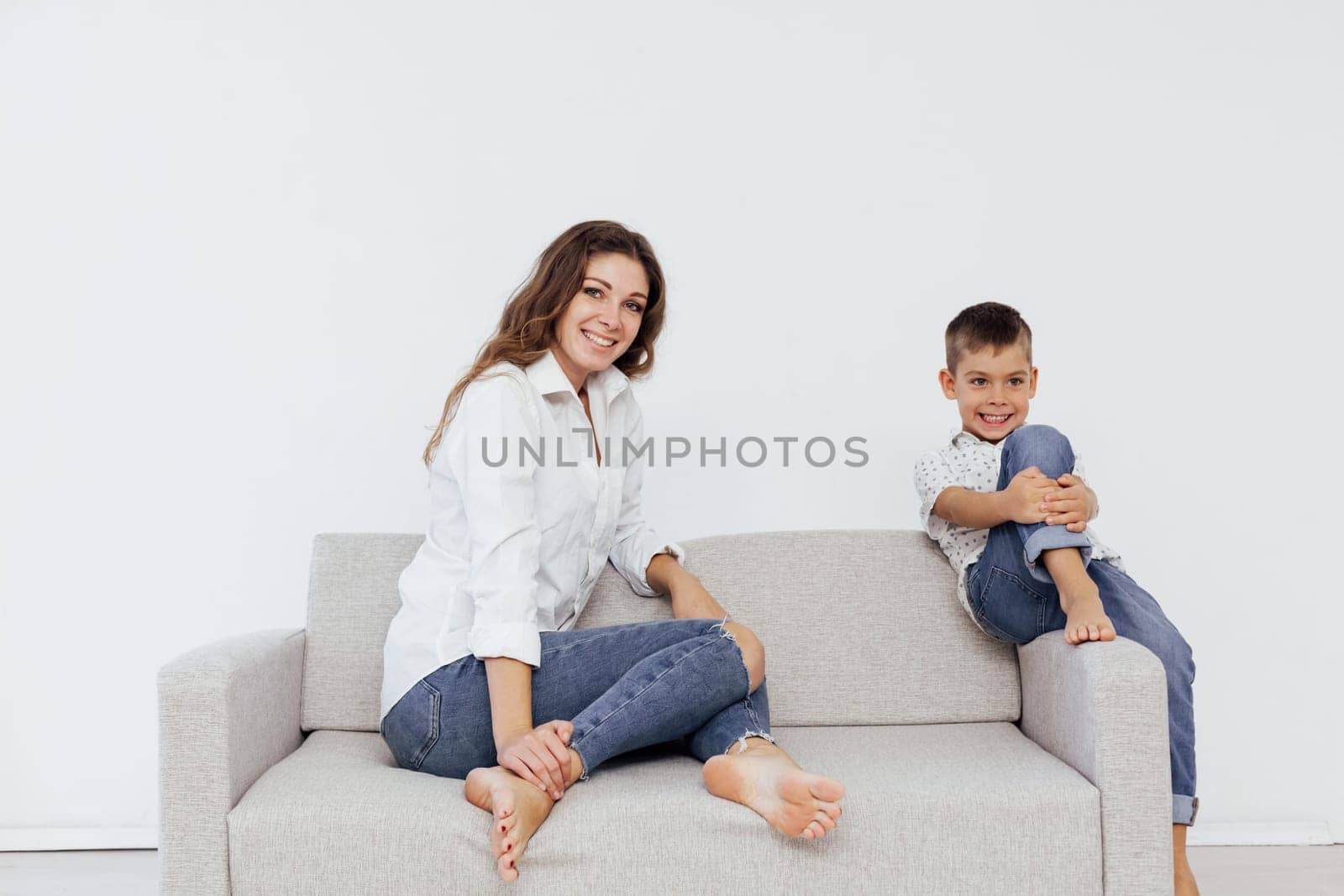 woman sits on the couch next to a cheerful child in a bright room