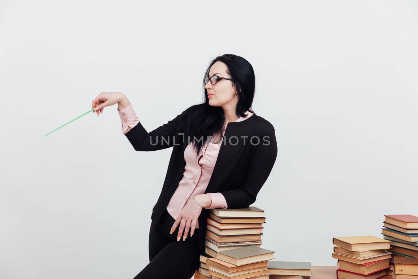 a teacher with a school pointer stands at a stack of books by Simakov