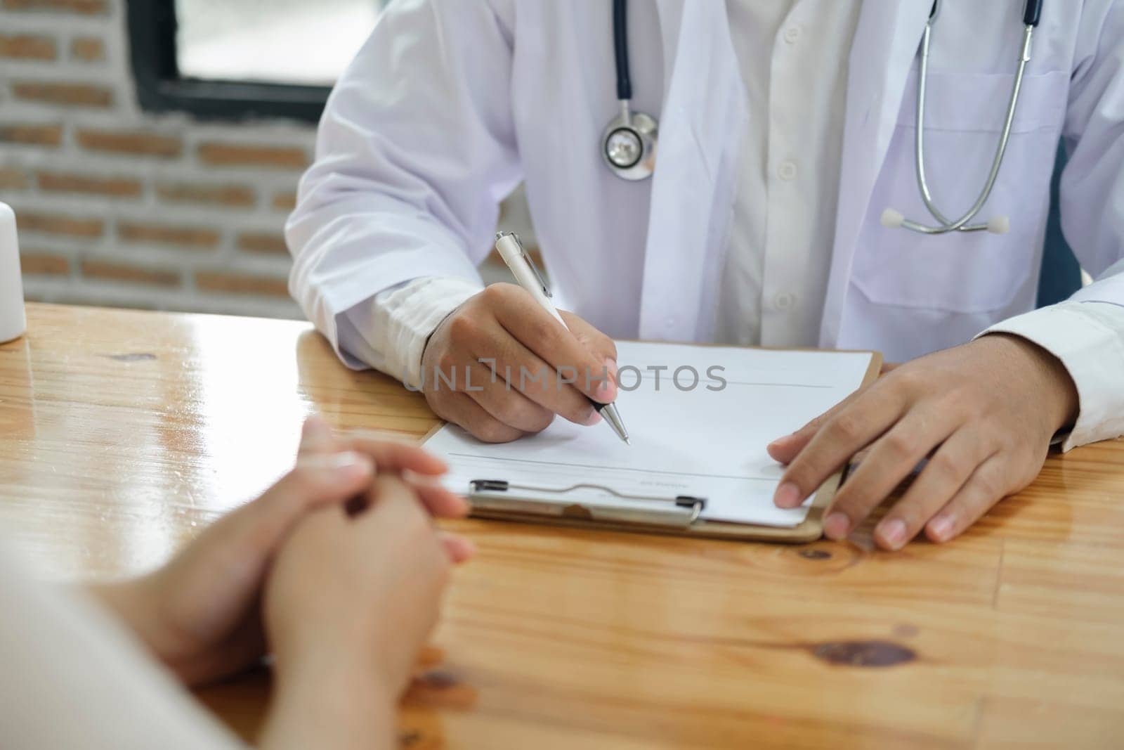 Doctor and patient. Close up of doctor explaining diagnosis and discussing treatment plans to patient with prescription in doctor office. Medical and health care concept.