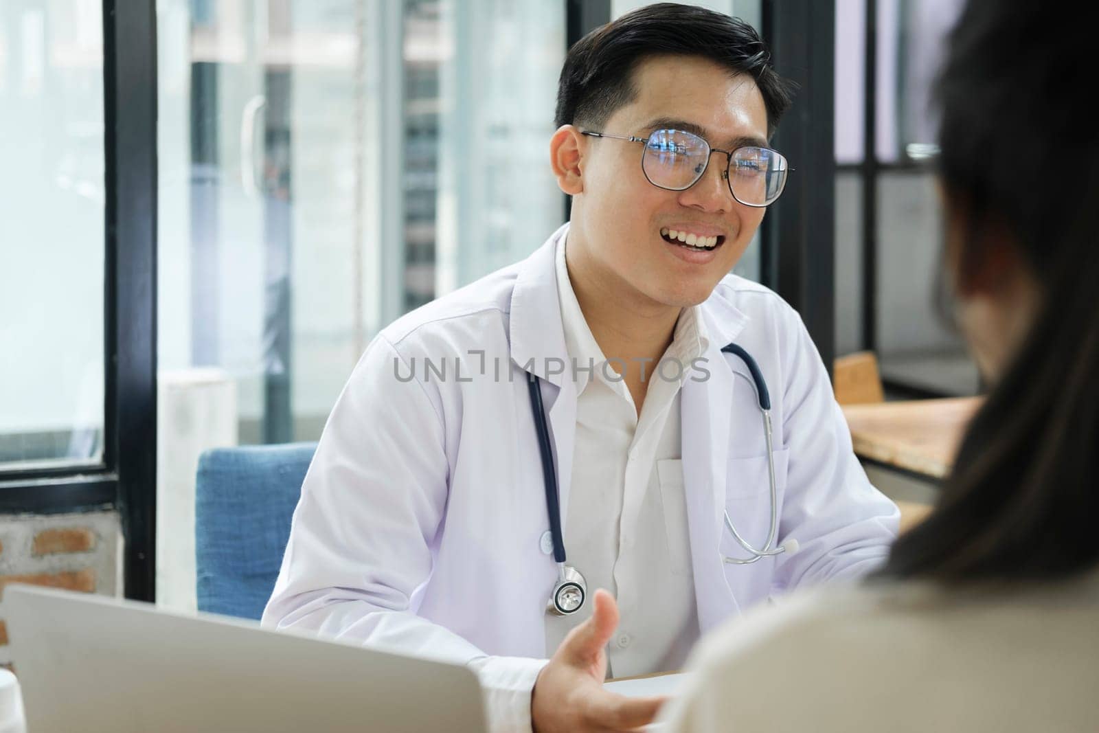 Medicine, healthcare and people concept. A doctor explaining diagnosis to patient. The physician doctor listening to patient during consultation while sitting down in the office of a modern medical center..