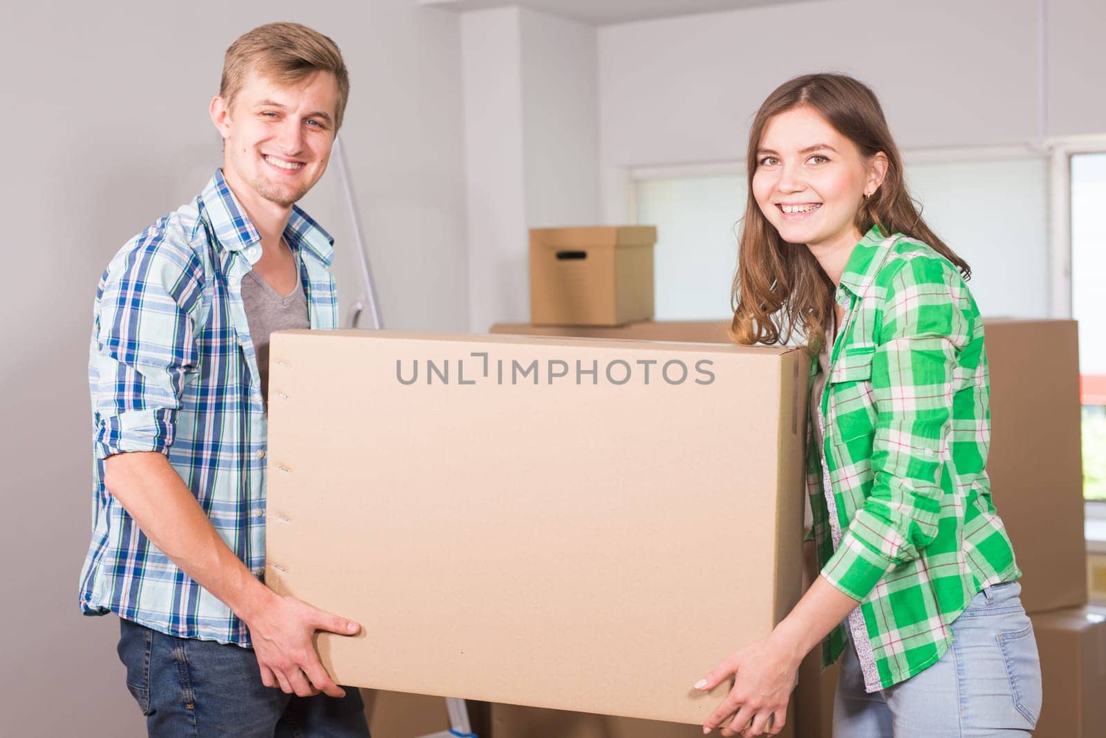 Happy young couple unpacking or packing boxes and moving into a new home. by Satura86