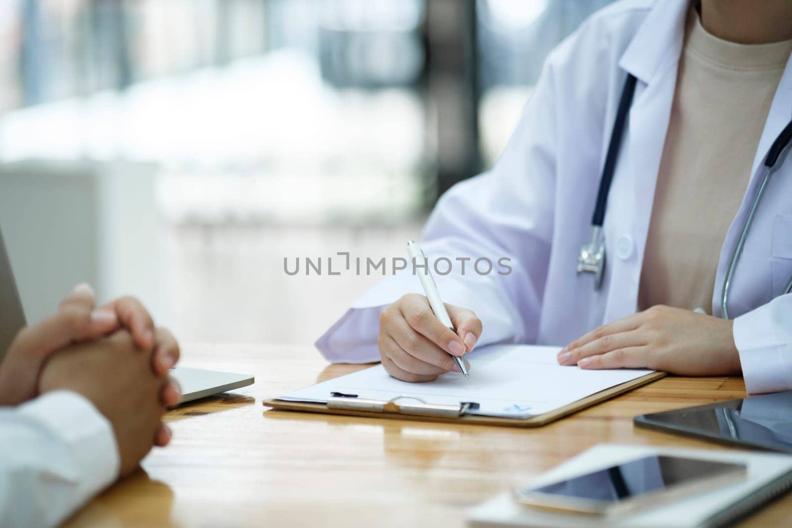Doctor and patient. Close up of doctor explaining diagnosis and discussing treatment plans to patient with prescription in doctor office. Medical and health care concept.
