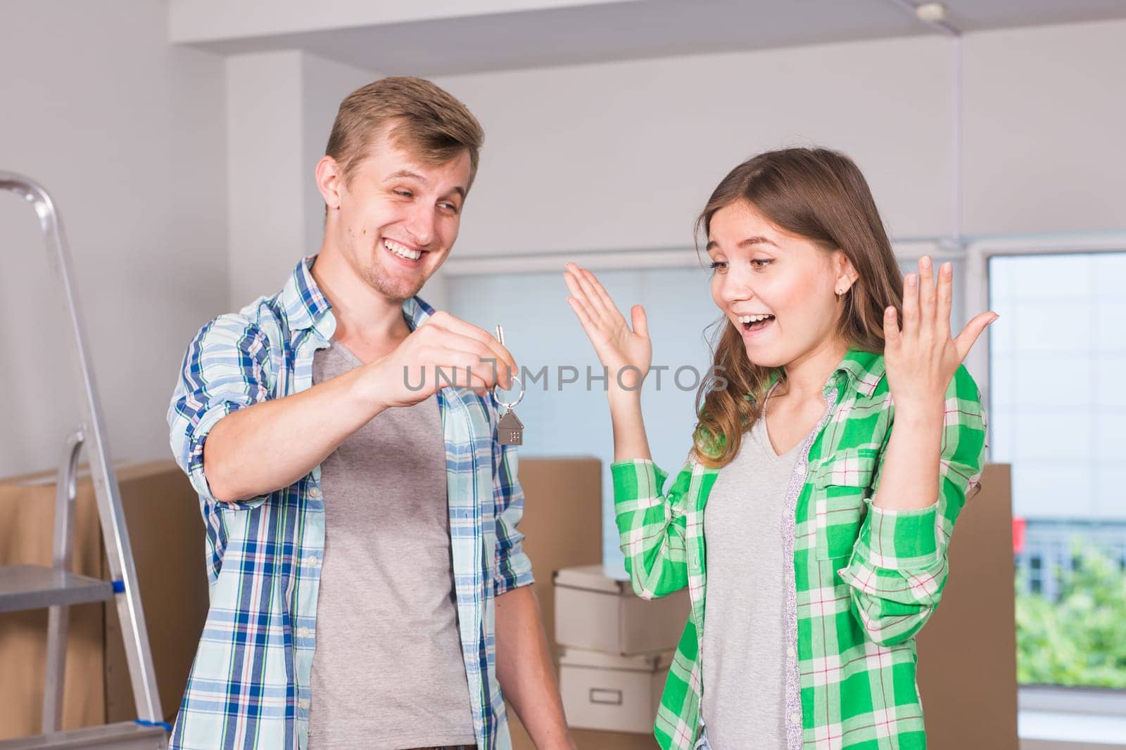 home, people, moving and real estate concept - Surprised woman looking at house keys in the hand of a man by Satura86