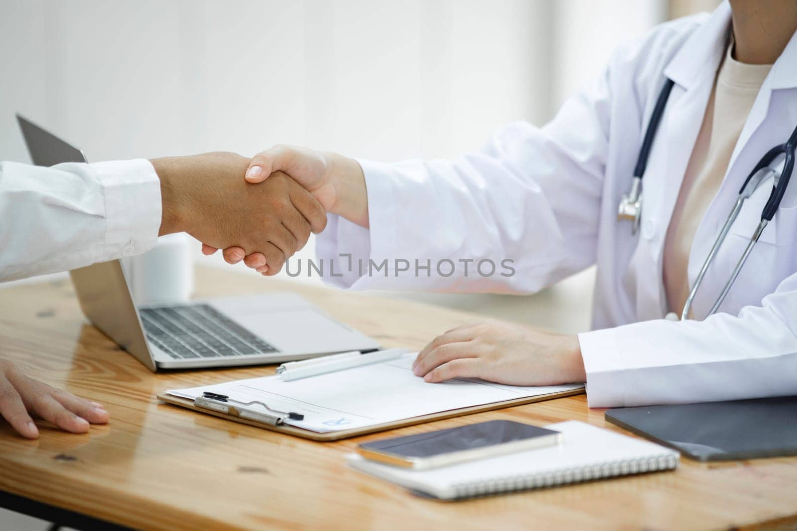 Doctor shacking patient hand after giving advice or doing health examination or medical checkup in hospital with white background and copy-space..