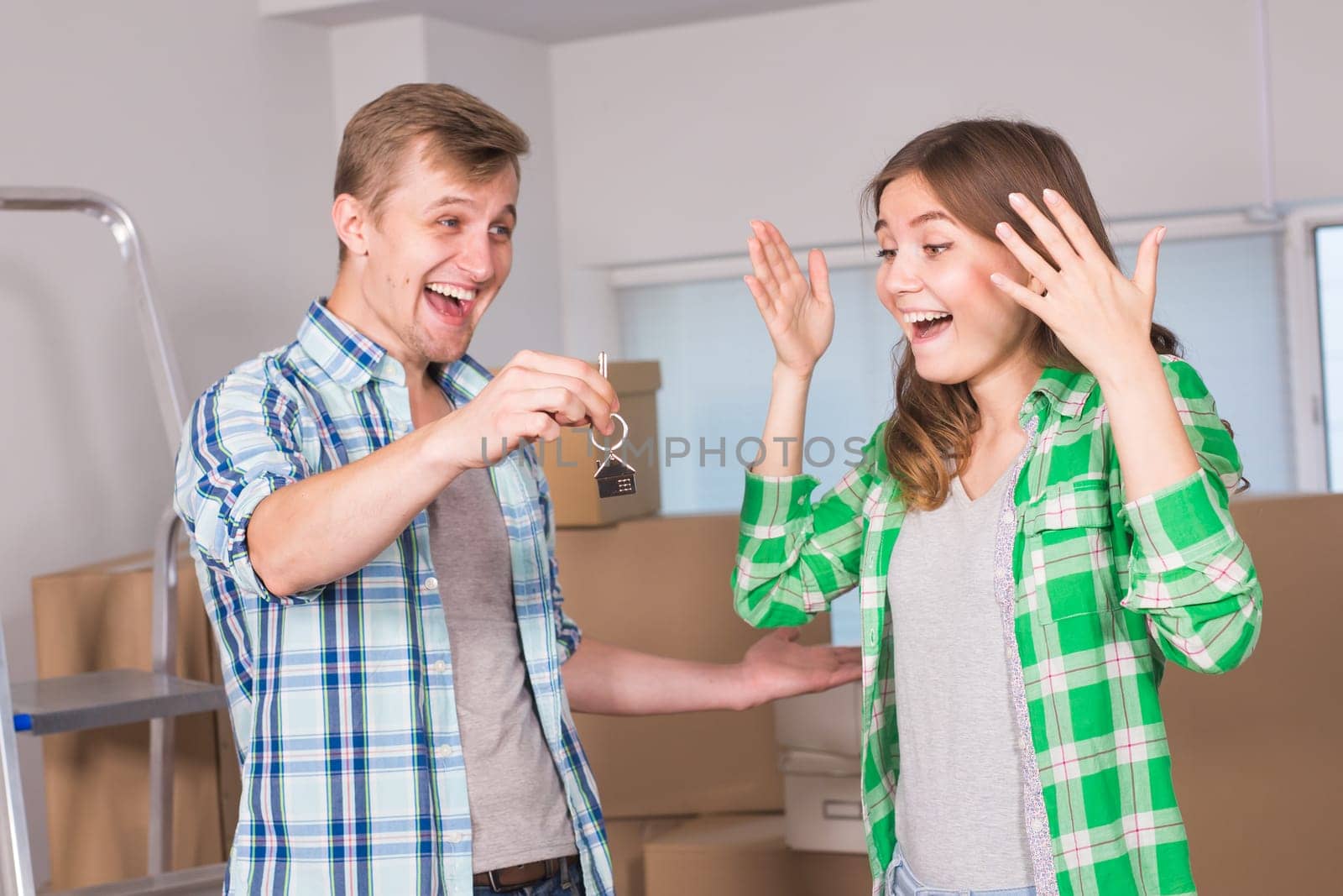 home, people, moving and real estate concept - Surprised woman looking at house keys in the hand of a man.