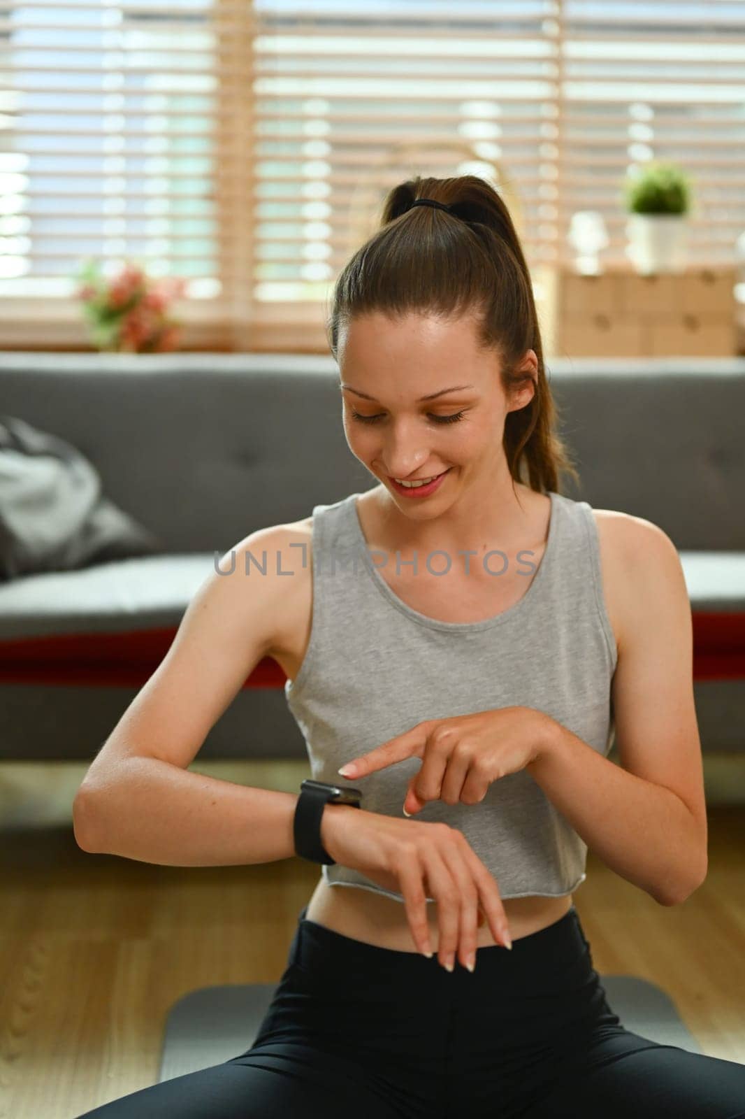 Sporty caucasian lady checking fitness tracker during workout at home.