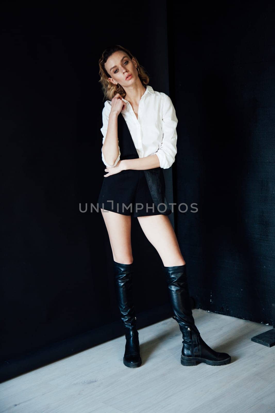 beautiful blonde in black boots poses on black background