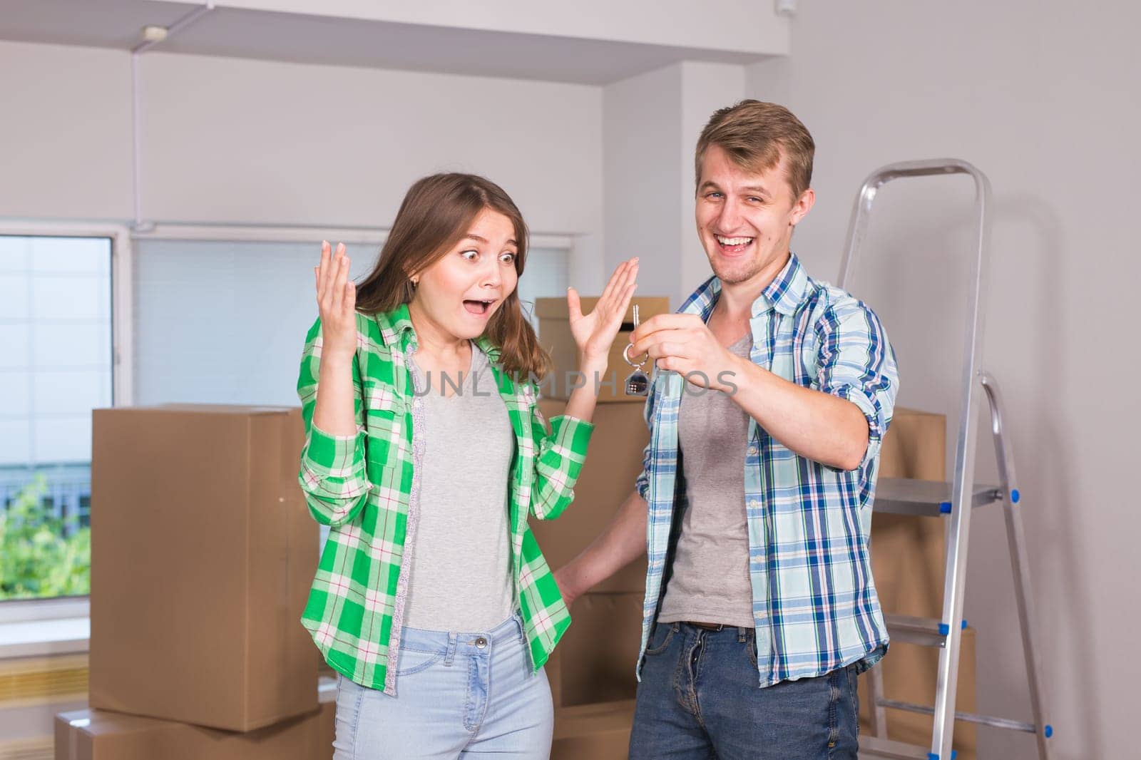 home, people, moving and real estate concept - Surprised woman looking at house keys in the hand of a man.