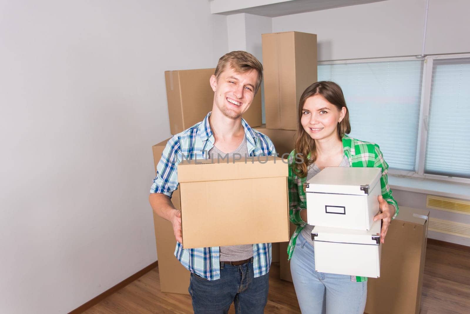 home, people, moving and real estate concept - happy couple with cardboard boxes at new home.