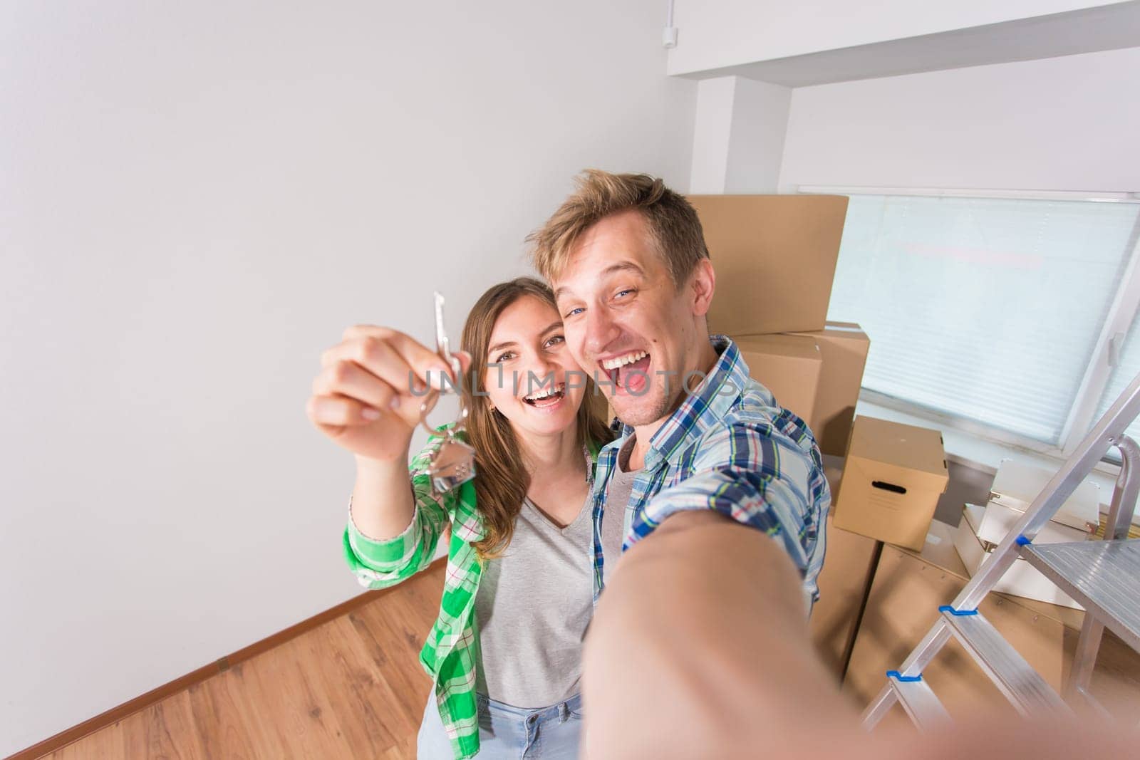 Happy couple showing keys of new home indoor