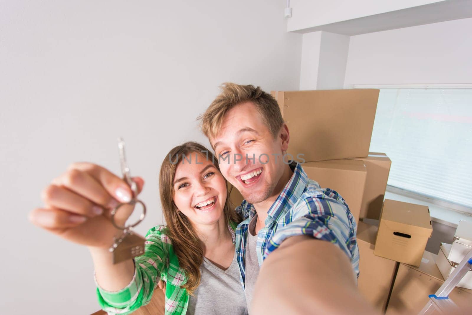 Happy funny couple embracing and showing house key in their new home by Satura86