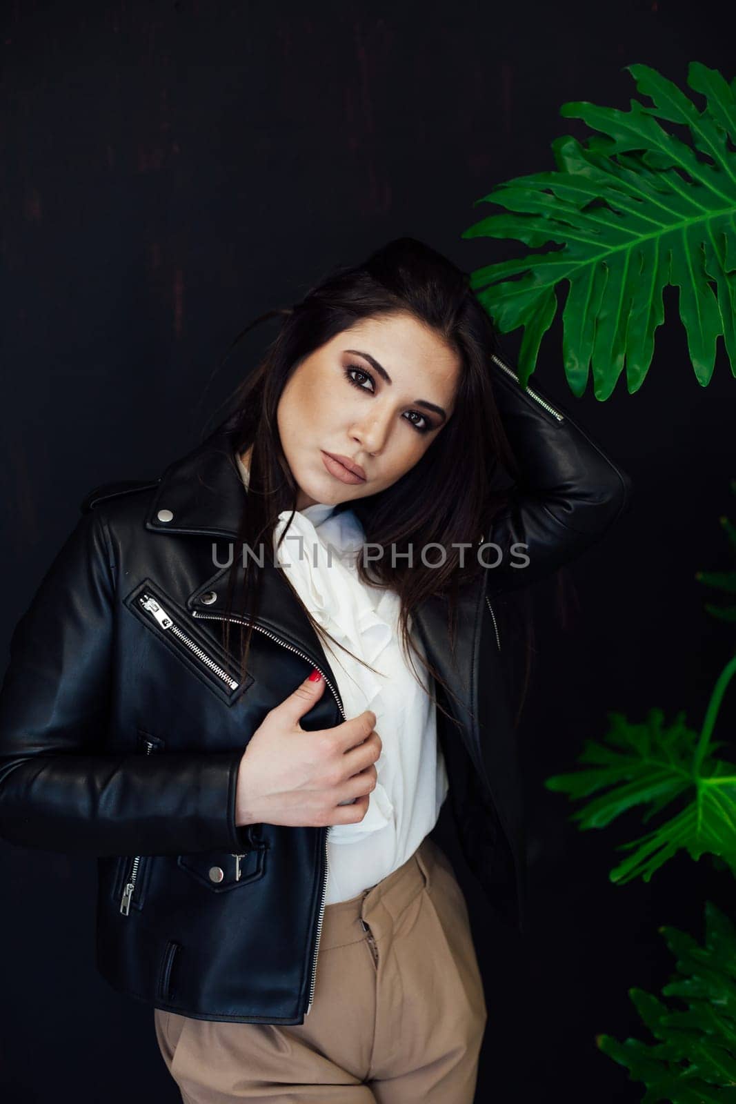 brunette woman near a green plant in greenhouse