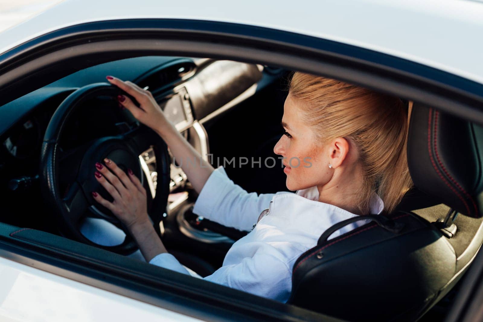 female driver behind the wheel of white car