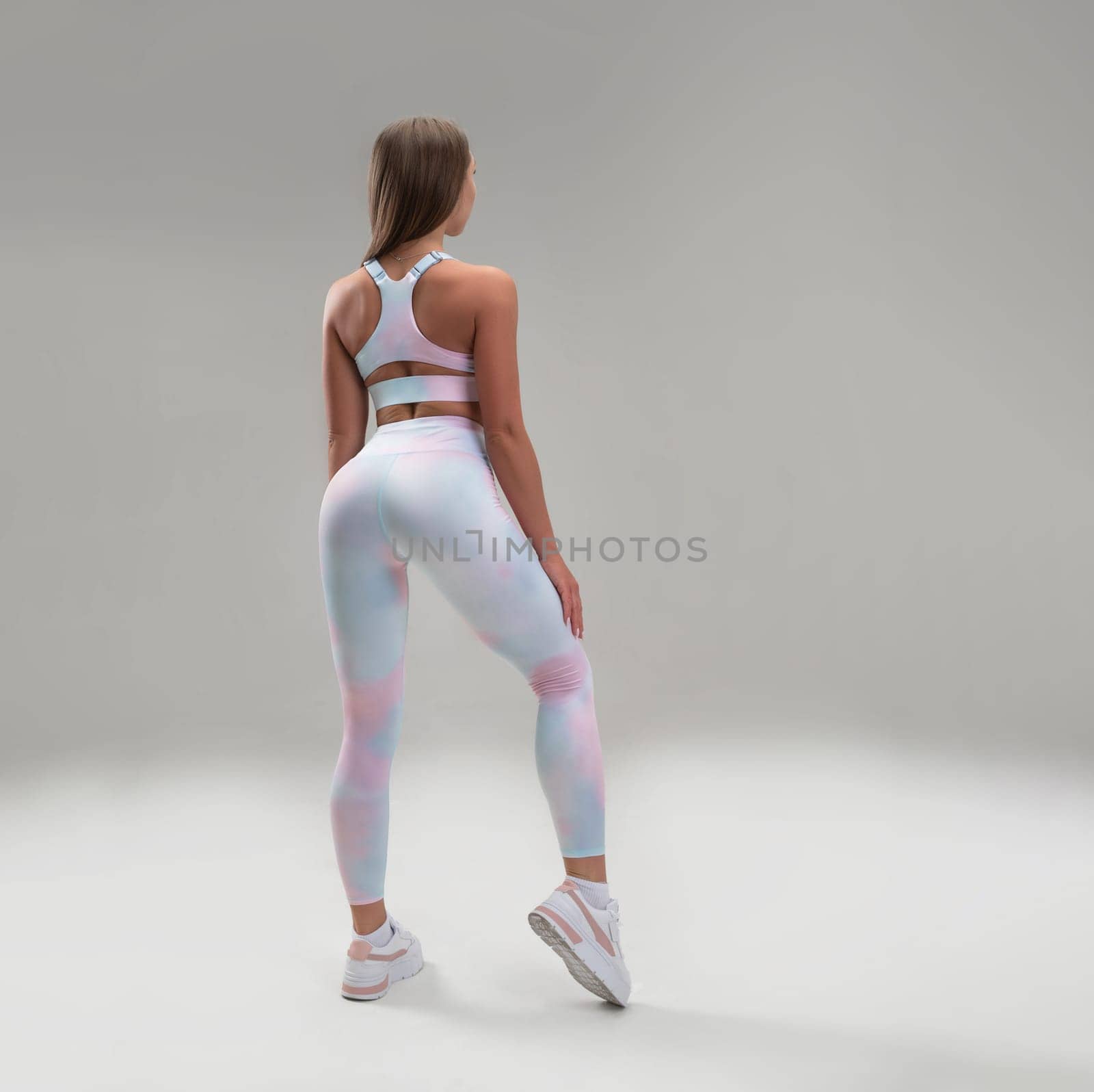 sexy athletic girl in a tight fitness tracksuit on a light background copy paste in studio