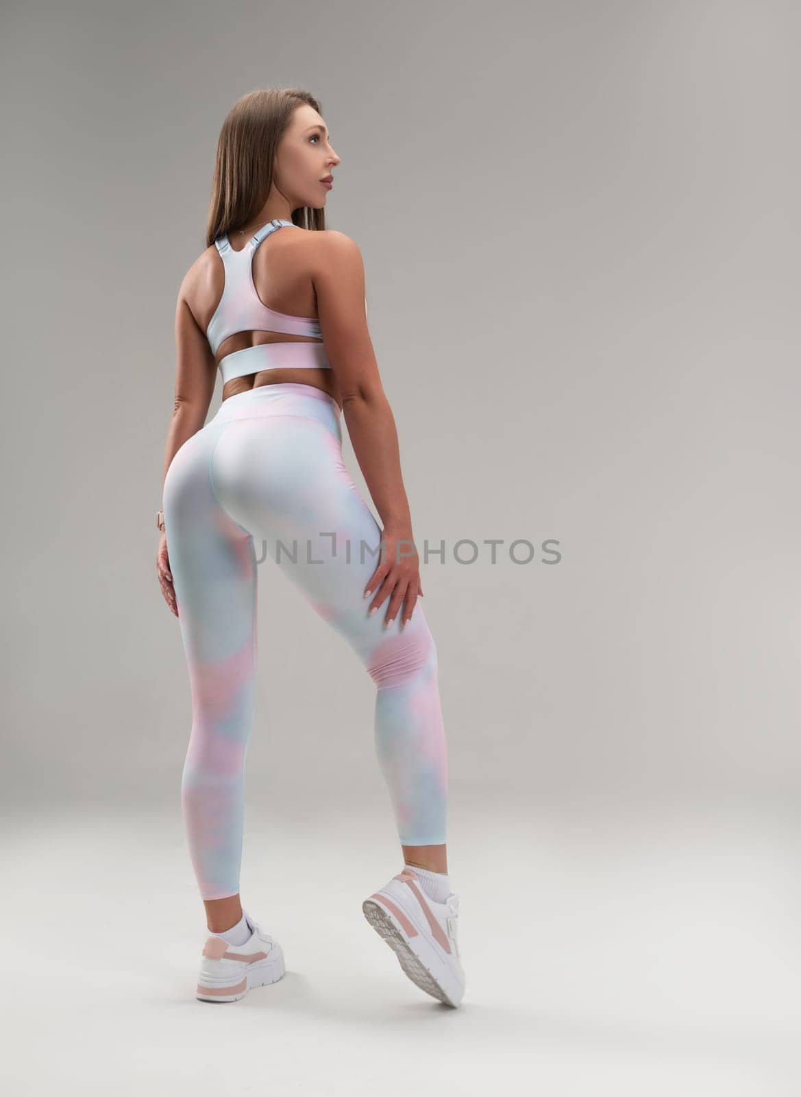 sexy athletic girl in a tight fitness tracksuit on a light background copy paste in the studio by Rotozey