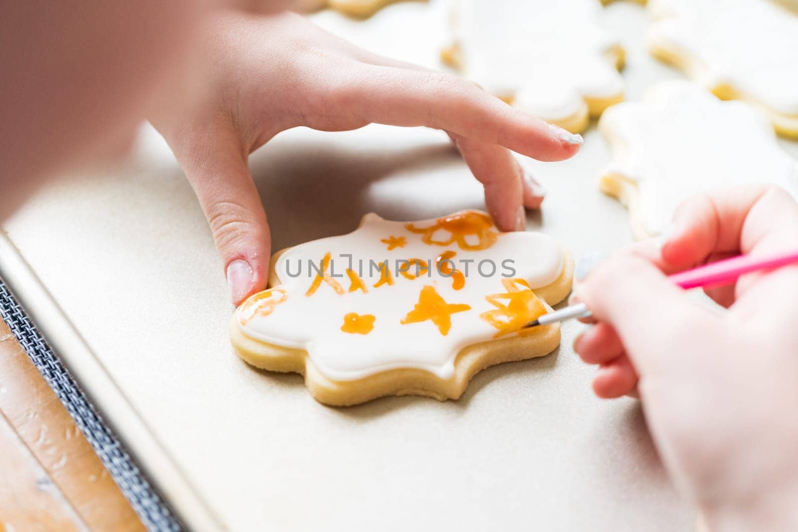 A heartwarming scene of a little girl carefully writing 'Sorry' on sugar cookies with food coloring, the cookies beautifully flooded with white royal icing.