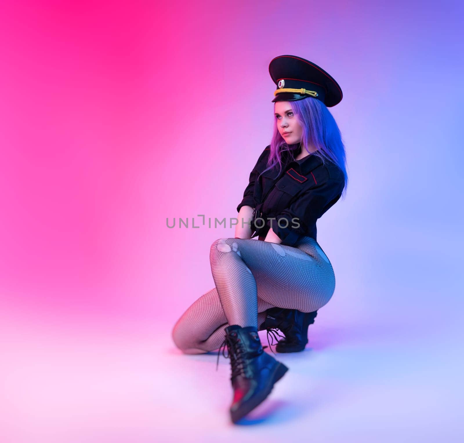 Sexy girl in police uniform for sexual games with handcuffs in neon light on the light background