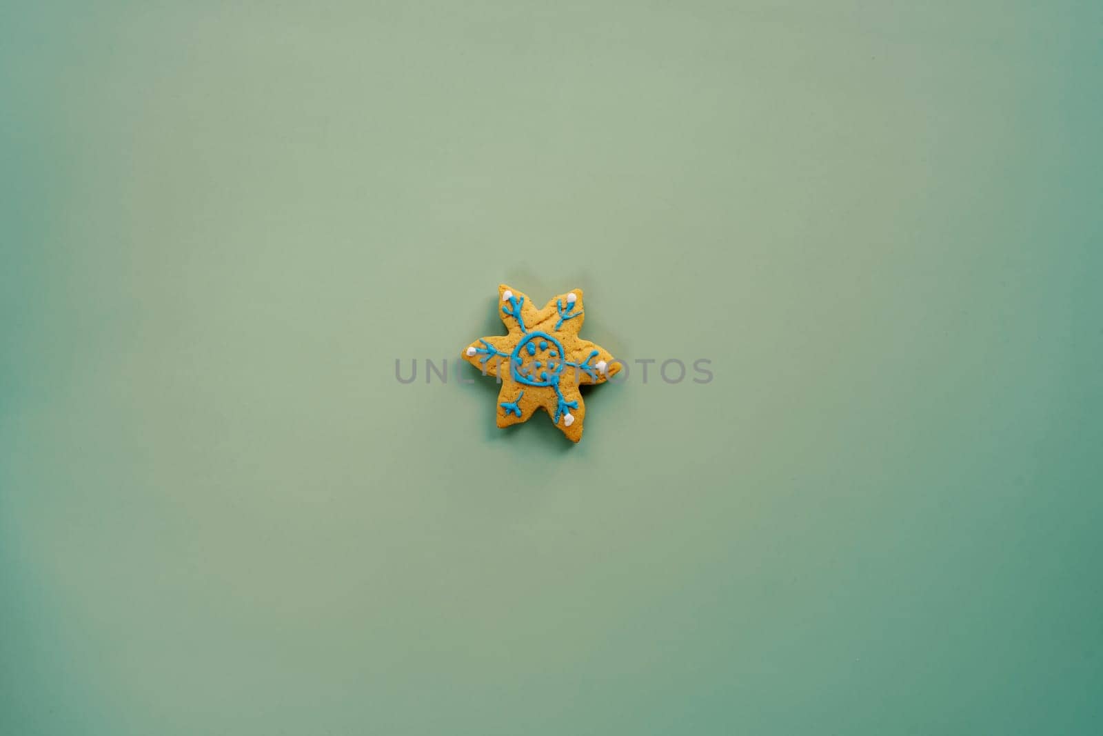 Glazed cookies in the shape of a snowflake lies on a green background. High quality photo