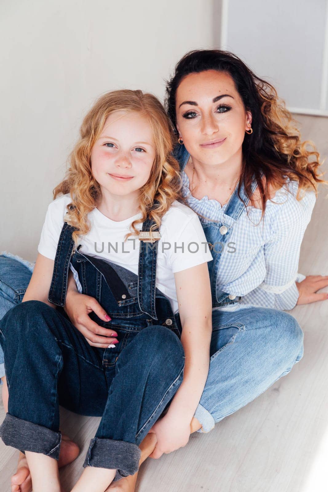 mother and daughter family look sitting on the floor in hug