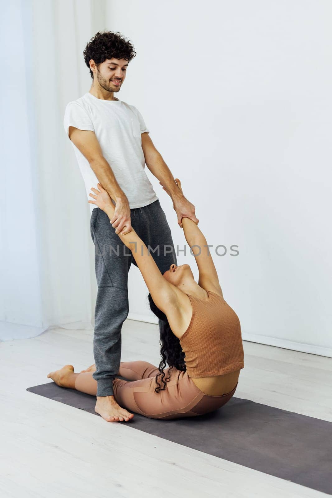 trainer stretches hands in yoga classes acrobats by Simakov