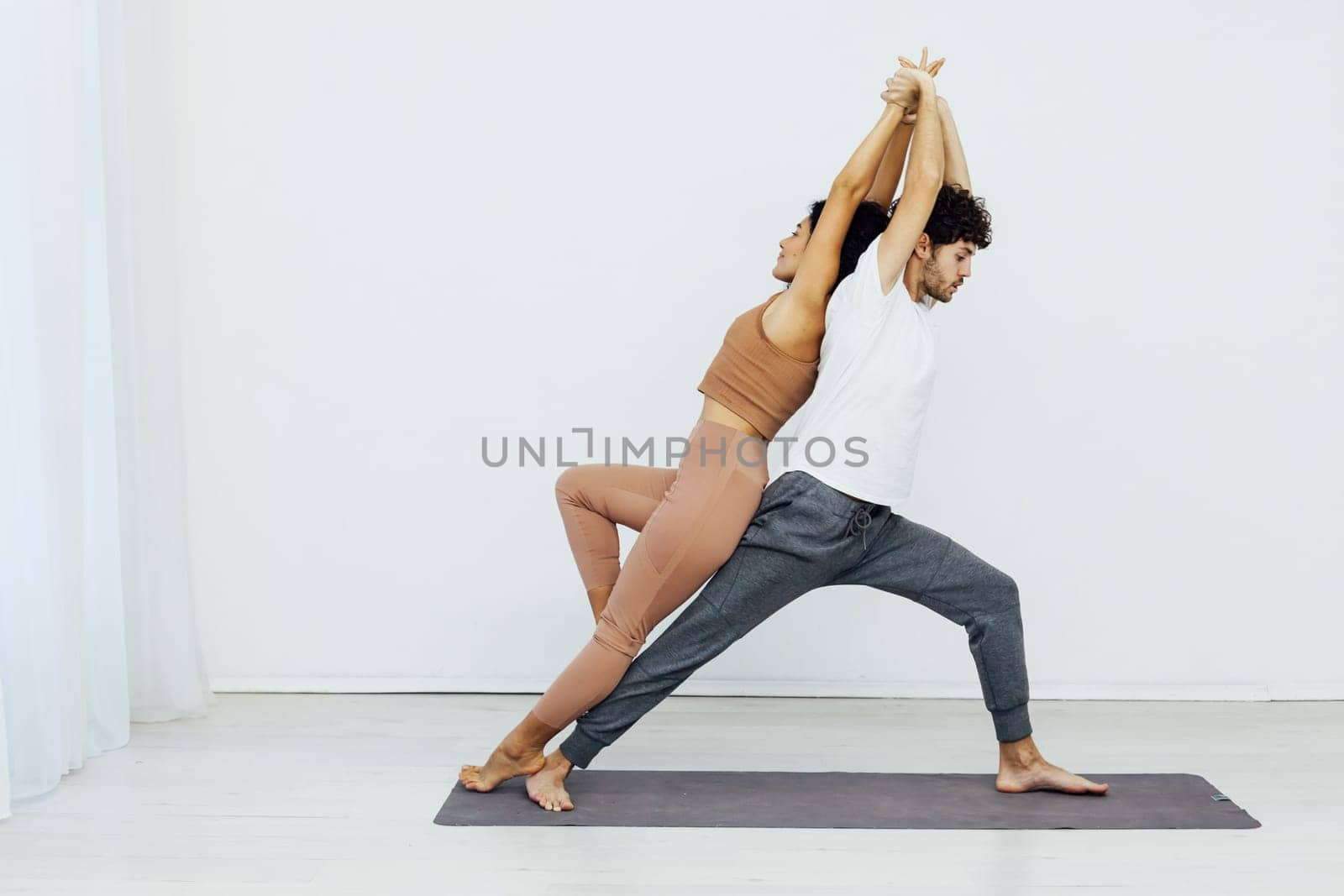 coach stretches a woman's back with yoga in the gym by Simakov