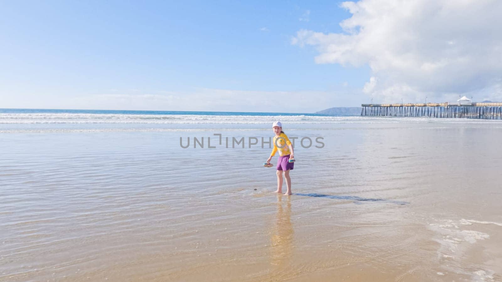 Little Girl Joyfully Running on Winter Beach by arinahabich