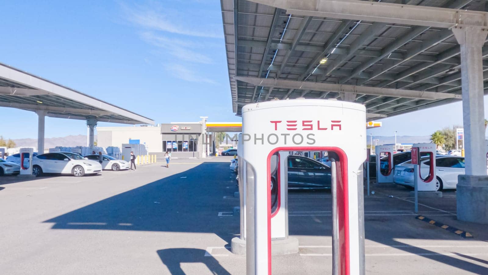 Baker, California, USA-December 3, 2022-During the day, a Tesla vehicle is seen charging at a Tesla Supercharging station, utilizing the high-speed charging infrastructure for convenient and efficient electric vehicle refueling.