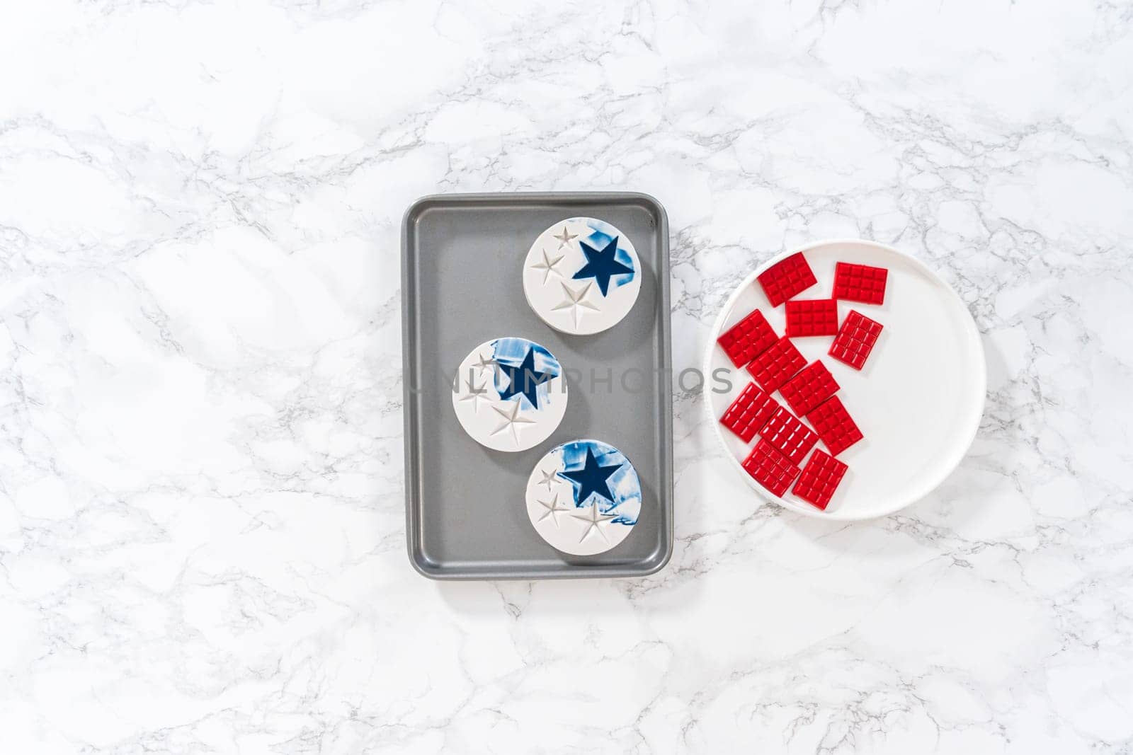 Flat lay. Filling silicone mold with red and blue melted chocolate to make chocolate stars for patriotic lemon cupcakes.