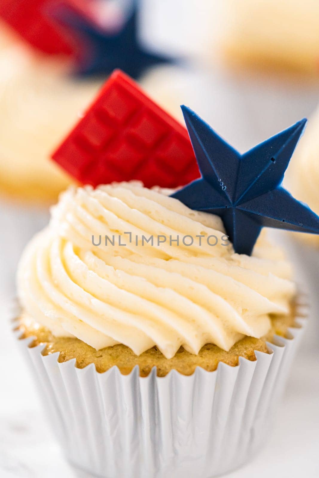 Lemon cupcakes with lemon buttercream frosting, and decorated with patriotic blue chocolate star and red mini chocolate.