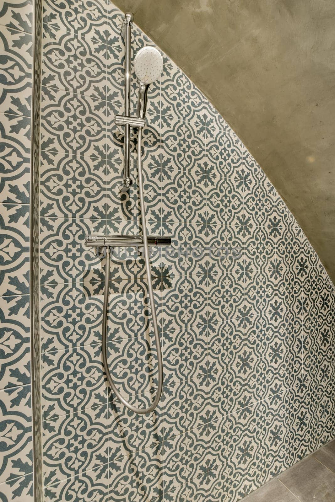 a shower with blue and white tiles on the floor by casamedia