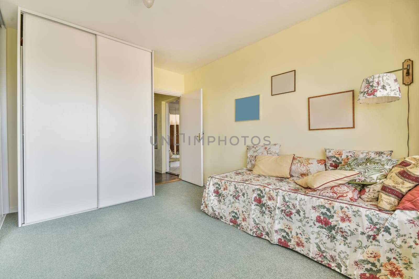 a living room with yellow walls and floral bed spread across the room, there is an open door leading to another room