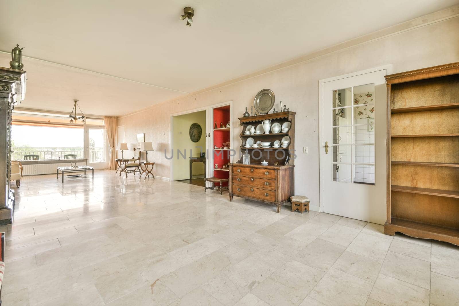 a living room with white tile flooring and large open doors leading to an outdoor patio area that overlooks out onto the street