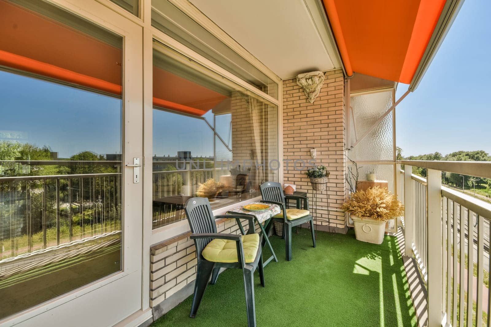 a balcony with chairs and tables on the grass area, looking out onto the street from the front door to the view is clear