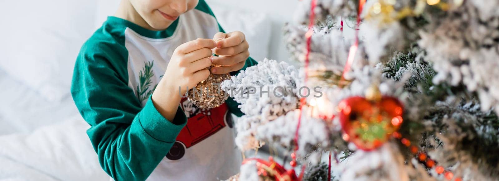 Banner Child decorates Christmas tree copy space mockup. The boy is holding a Christmas toy. Morning before christmas at home. Generation alpha and gen alpha children. by Satura86