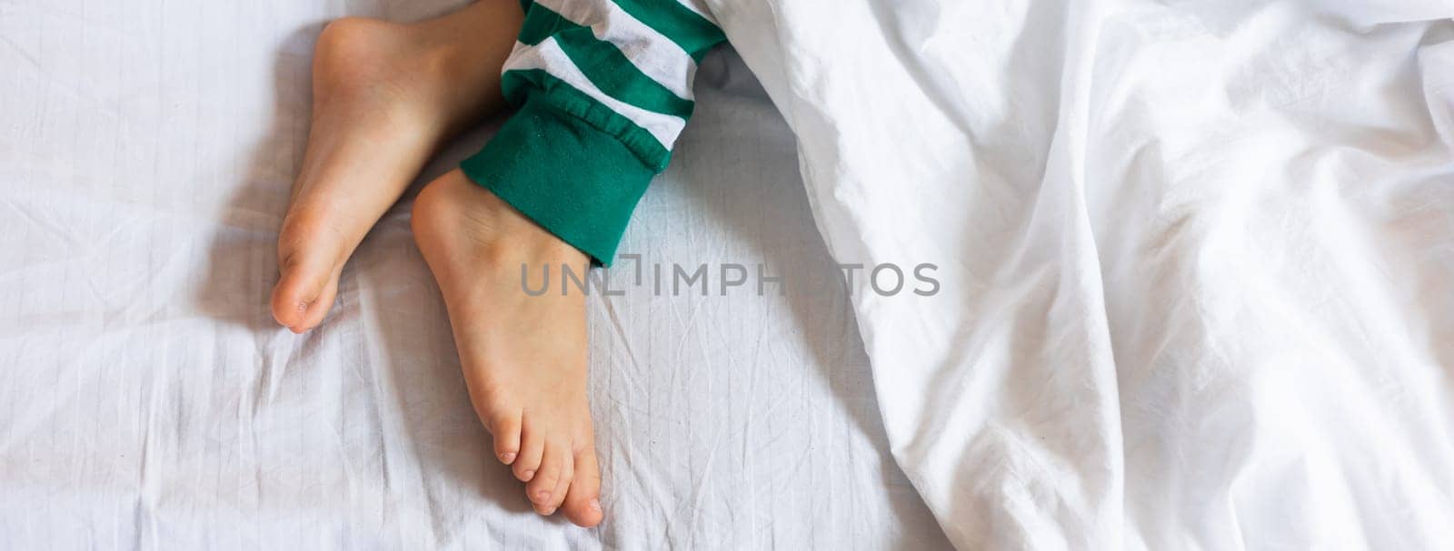 Banner child feet under the white blanket. Copy space and empty space for text, mockup by Satura86