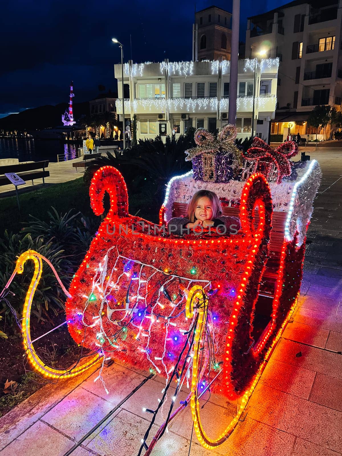Little girl sits in Santa sleigh glowing with lights. High quality photo