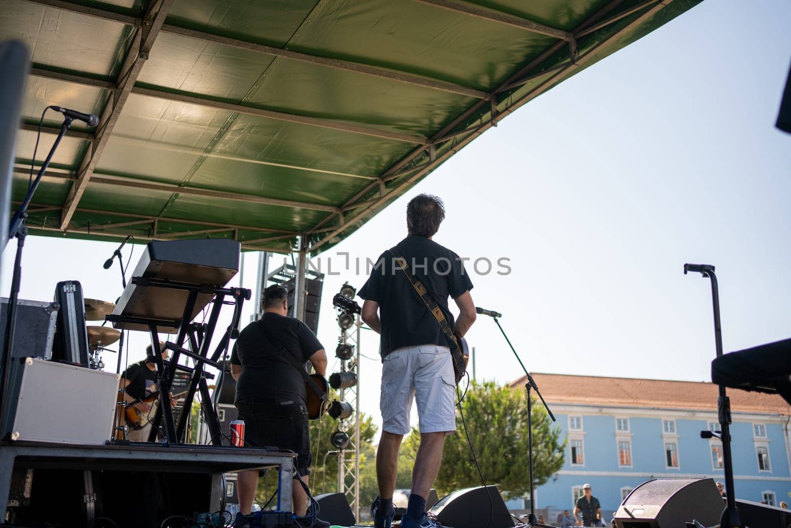 Band performing in front of the audience. View from backstage at concert. Musicians playing guitars during an open concert. Artists on tour during live performance