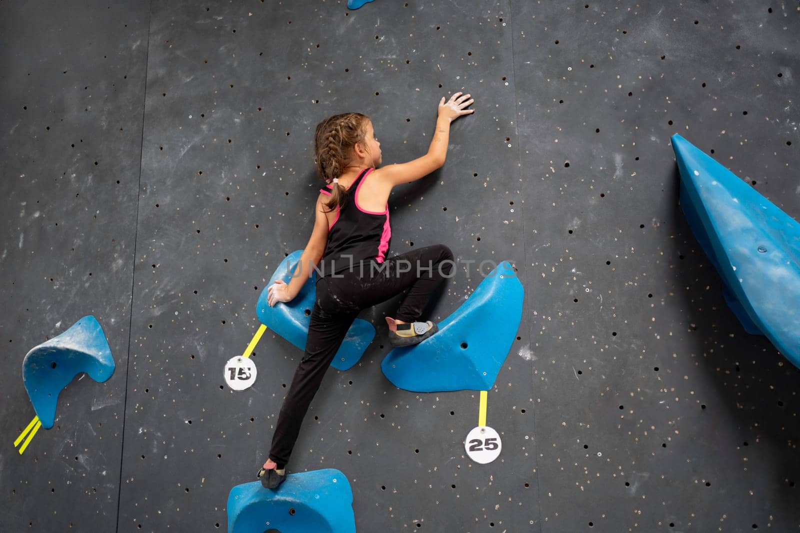 Little girl in sportswear is climbing wall entertainment center by andreonegin