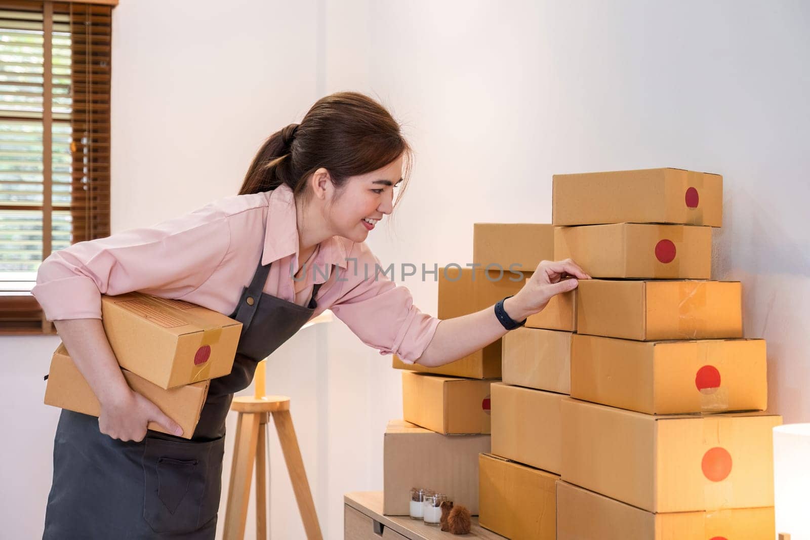 Portrait of starting a small business SME business owner Female entrepreneur working on merchandise boxes Receipts and checks online orders to prepare boxes for seller to customers. by wichayada