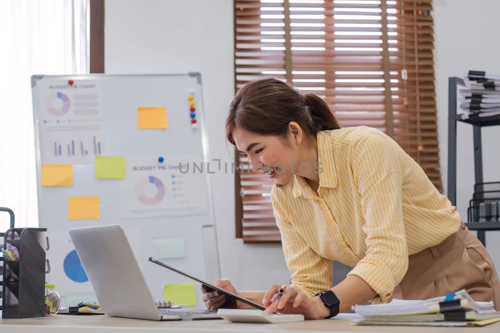 Business woman using calculator and laptop for do math finance on wooden desk in office and business working background, tax, accounting, statistics and analytic research concept.