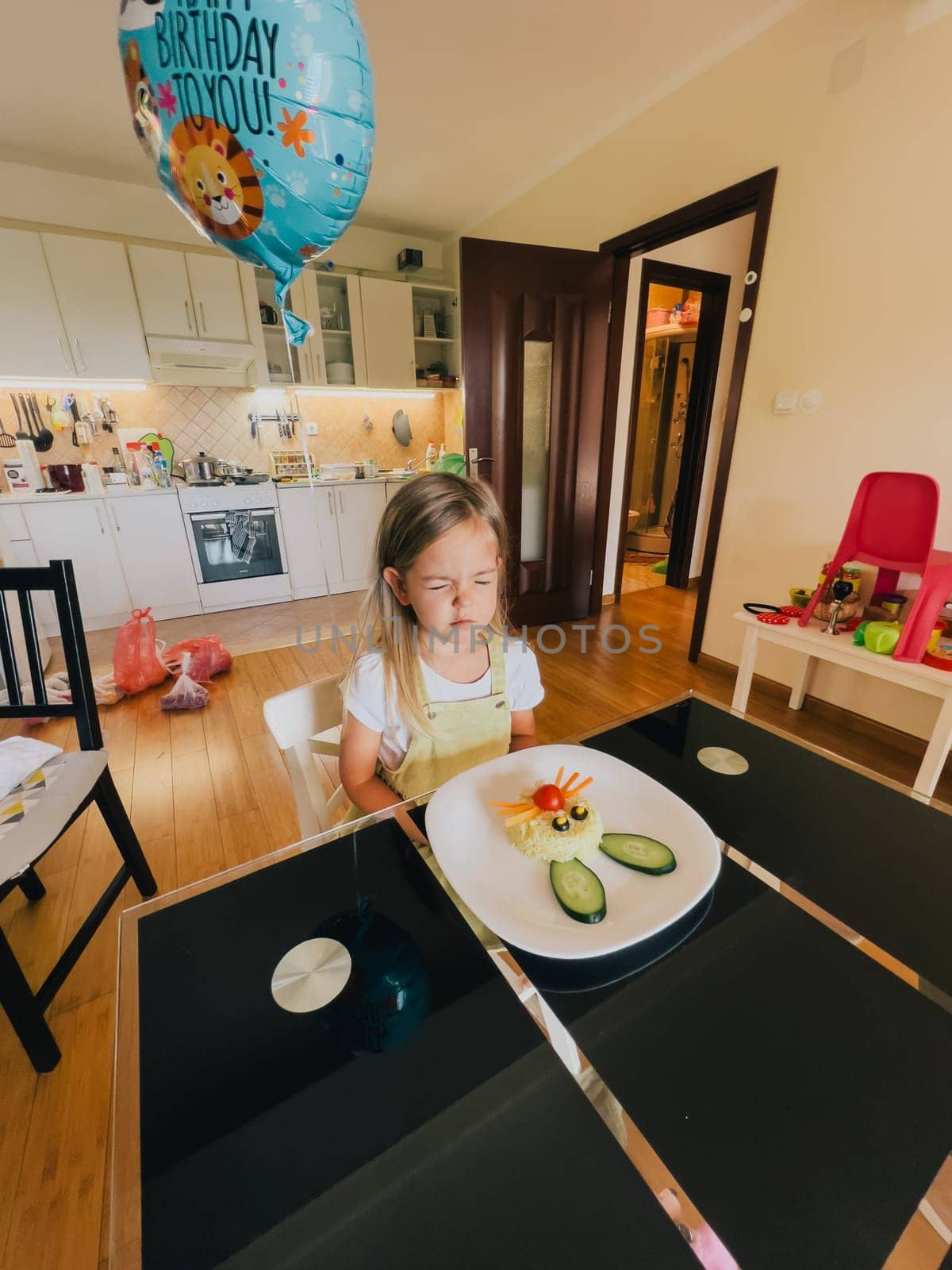 Little birthday girl sits in front of a plate of rabbit-shaped rice at the table. High quality photo