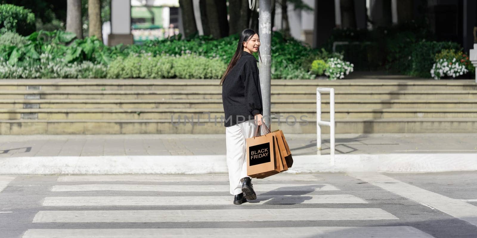 Young asian woman in shopping. Fashion woman in black with shopping bag walking around the city after shopping. Black friday.